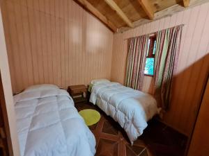 2 camas en una habitación pequeña con ventana en Cabanas El Cipres, en Pucón