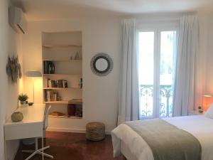 um quarto com uma cama, uma secretária e uma janela em Coup de Cœur VIEUX PORT-République em Marselha
