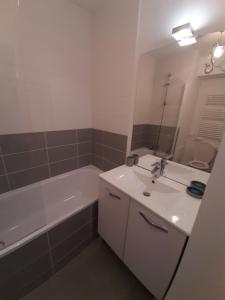 La salle de bains est pourvue d'un lavabo blanc, d'une baignoire et d'un miroir. dans l'établissement charmant appartement en plein coeur de Trouville, à Trouville-sur-Mer