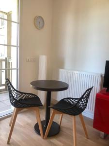 une table et deux chaises dans une pièce avec une horloge dans l'établissement charmant appartement en plein coeur de Trouville, à Trouville-sur-Mer