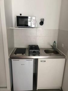 a small kitchen with a stove and a microwave at charmant appartement en plein coeur de Trouville in Trouville-sur-Mer