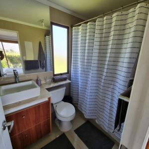 a bathroom with a toilet and a sink and a window at Casa de Campo Viña el Campesino con Tinaja Caliente y Piscina in Melipilla