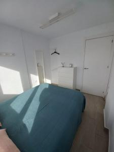 a bedroom with a blue bed in a white room at Apartamento moderno frente a la playa San Miguel in El Rompido