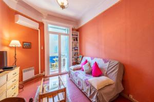 ニヨンにあるLe Pontiasのオレンジ色の壁のリビングルーム、ピンクの枕付きのソファが備わります。