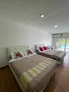 two large beds in a bedroom with at บ้านสวนแม่น้ำ-บ้านพูลวิลล่า in Ban Kao