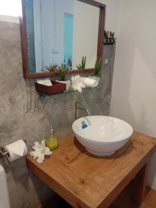 a bathroom with a white bowl sink on a wooden counter at บ้านสวนแม่น้ำ-บ้านพูลวิลล่า in Ban Kao