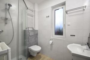 a white bathroom with a toilet and a sink at Szafir Apartamenty in Sianozety