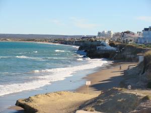 a beach with people walking on the sand and the ocean at Calfulauquen in Las Grutas
