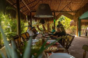 un grupo de personas sentadas en una mesa larga en Pousada Morada dos Ventos, en Pipa