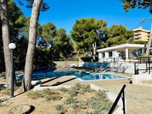 a swimming pool with trees and a house at BOOK RITS SALOU in Salou