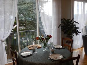 une table avec des assiettes et des fleurs devant une fenêtre dans l'établissement Studio Quartier Château - Wifi - Garage individuel à clé - Electroménager complet, à Pau