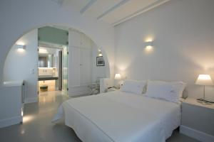 a white bedroom with a large bed and a bathroom at Zoe's Club in Spetses