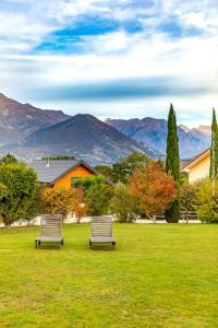 two benches sitting in a field with mountains in the background at Maison dans les Alpes - Gîte les 12 sommets in Ponsonnas