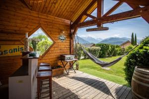 um alpendre de um chalé de madeira com uma rede de descanso em Maison dans les Alpes - Gîte les 12 sommets em Ponsonnas