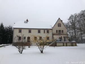 a large white house with snow on the ground at Ferienwohnung "Altes Schloss Wilhelmsfeld" 
