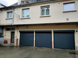 drie garagedeuren aan de zijkant van een gebouw bij Au perron avec garage et balcon à Ribeauville in Ribeauvillé