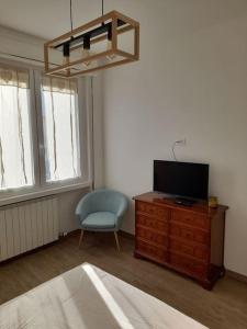 a bedroom with a tv on a dresser and a chair at Casa Vacanza "Aurora" in Costa Volpino