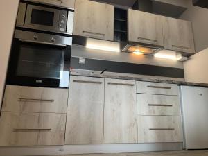 una cocina con armarios de madera y electrodomésticos de acero inoxidable en Backyard Apartment, en Miskolc