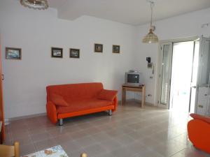 a living room with an orange chair and a tv at Villa Monica appartamenti in Vieste