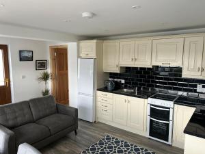 a kitchen with white cabinets and a couch in a room at The Dingle Galley in Dingle