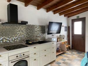 a kitchen with a sink and a tv on the wall at La Cuadra de Pascuala in Tajace de Abajo