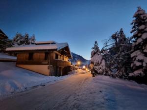 a snow covered road in front of a cabin at Chalet le Petit Ramoneur in Châtel