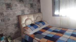 a bedroom with a white bed with a checkeredkered at Appartement au calme hors du bruit de Casablanca à Bouskoura in Bouskoura
