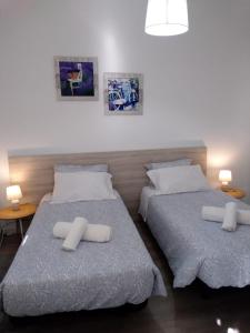 two beds in a room with two tables and two pillows at Apartamento Balsa 2 in Viseu