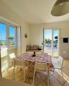 Un comedor con una mesa con sillas blancas y una habitación con ventanas. en Villa li Specchi, en Racale