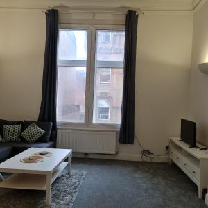 a living room with a couch and a table and a window at Regent Apartments - Glasgow City Centre in Glasgow