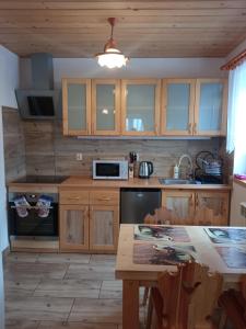 a kitchen with wooden cabinets and a table with a microwave at Domek w Pieninach in Grywałd