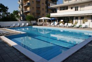 une grande piscine avec des chaises et un bâtiment dans l'établissement Hotel B&B Avana, à Lido di Savio