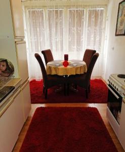 eine Küche mit einem Tisch mit Stühlen und einem roten Teppich in der Unterkunft Apartman stan na dan Sarajevo in Sarajevo