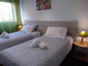 two beds in a room with a table and a lamp at Apartamento Balsa in Viseu