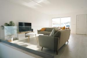 ein Wohnzimmer mit einem Sofa und einem TV in der Unterkunft Queen Villa - Santa Barbara - Lourinha in Mariquiteira
