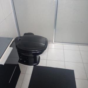 a toilet in a bathroom with a black seat at APTO FRENTE PARA MAR BOQUEIRÃO - PRAIA GRANDE in Praia Grande