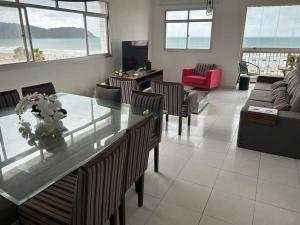 a living room with a glass table and chairs at APTO FRENTE PARA MAR BOQUEIRÃO - PRAIA GRANDE in Praia Grande
