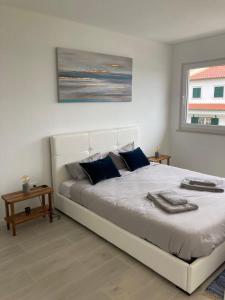 ein Schlafzimmer mit einem großen weißen Bett mit blauen Kissen in der Unterkunft Queen Villa - Santa Barbara - Lourinha in Mariquiteira