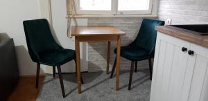 two green chairs and a wooden table in a kitchen at Sophie's Emerald Studio apartment in Podgorica