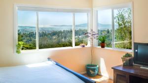 a bedroom with a bed and windows with a view at Magical Bay View in Oakland Hills in Oakland