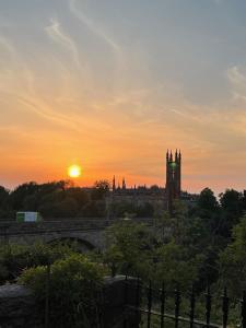 una puesta de sol sobre una ciudad con una torre de reloj en West End Townhouse en Edimburgo