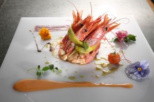 a white plate with a fish with vegetables on it at Camere La Meridiana in Domodossola