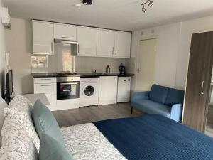 a kitchen with white cabinets and a blue couch in a room at Studio Apartment in Seven Sisters in London