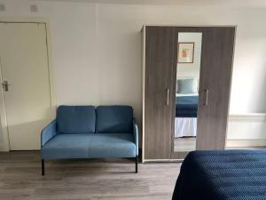 a blue chair in a room with a mirror at Studio Apartment in Seven Sisters in London