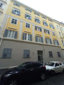 un coche negro y un coche blanco estacionado frente a un edificio en La Piccola Corte, en Trieste
