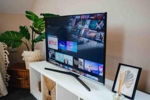 a flat screen tv sitting on top of a white table at Boho Loft in Somerset - Private Parking in Radstock