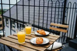 una mesa de madera con 2 vasos de zumo de naranja y cruasanes en Boho Loft in Somerset - Private Parking, en Radstock
