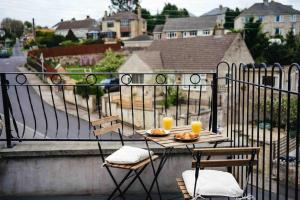 a table with two chairs and two drinks on a balcony at Boho Loft in Somerset - Private Parking in Radstock