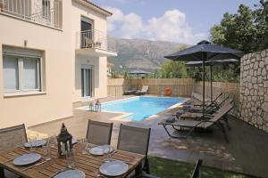 a patio with tables and an umbrella and a pool at Amarianos Villas in Agia Effimia