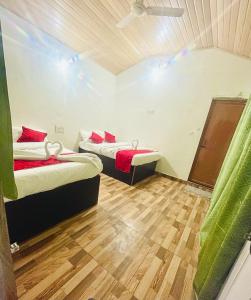 two beds in a small room with wood floors at Kanasucoffeenadu in Attigundi